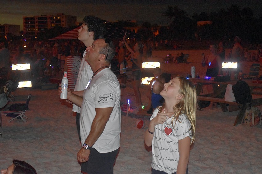 Luke Ribeiro, 17, his father Eric Ribeiro and Summer Reely, 9, look up at the fireworks from the sponsors and VIP area.