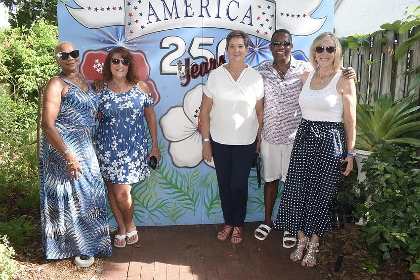 Patricia Greene, Shirley Skafec, Ginger Fannin, Wayne Liburd and Paula Rees stand in front of a background celebrating the country's 250th anniversary.