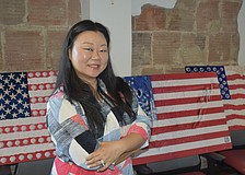 Jing Herman stands amongst prints of her artwork.