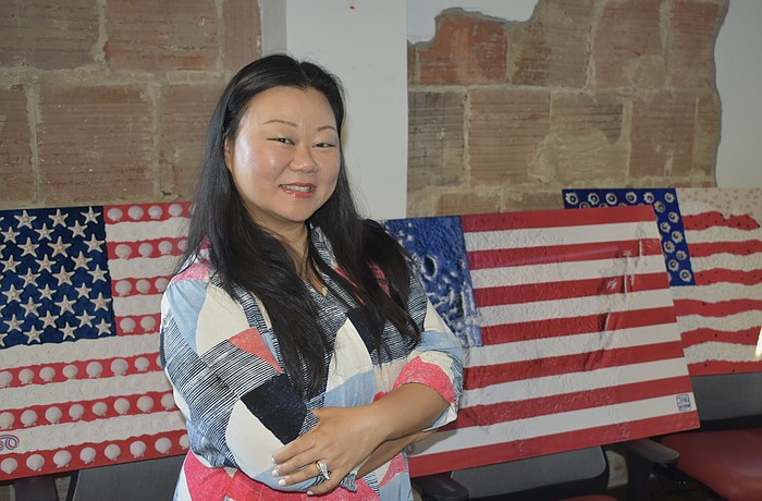 Jing Herman stands amongst prints of her artwork.