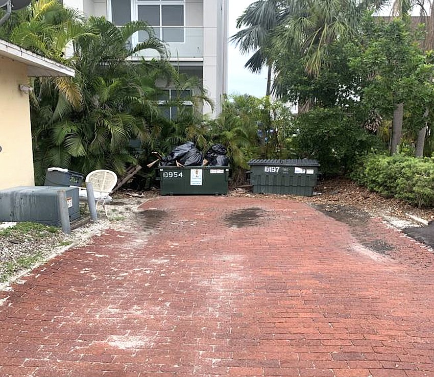 The terminus of Osprey Court ends at dumpsters overlooked by a neighboring condo building.
