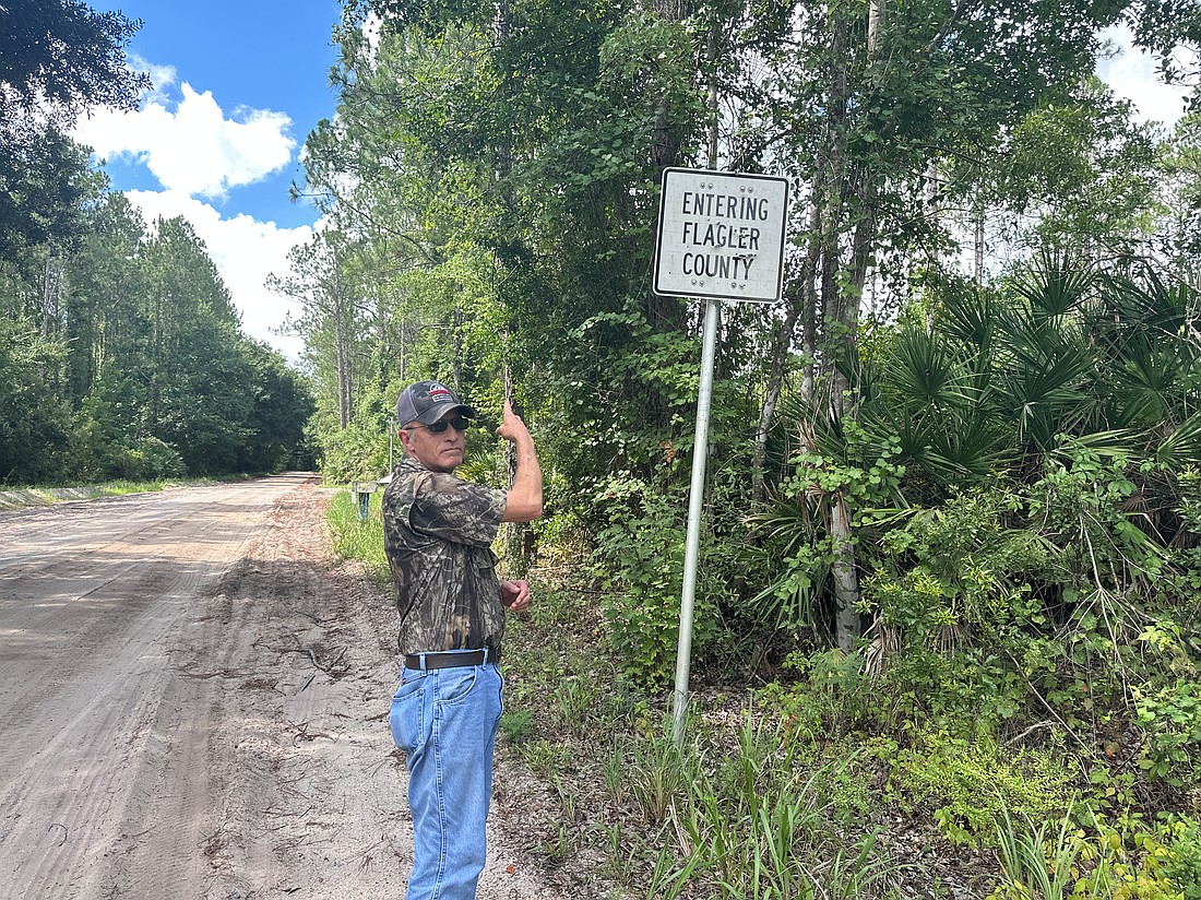 Palm Coast City Historian Preston Zepp points out the Flagler County line along the historic Dixie Highway, also known as Brick Road or County Road 13. Photo by Rich Carroll