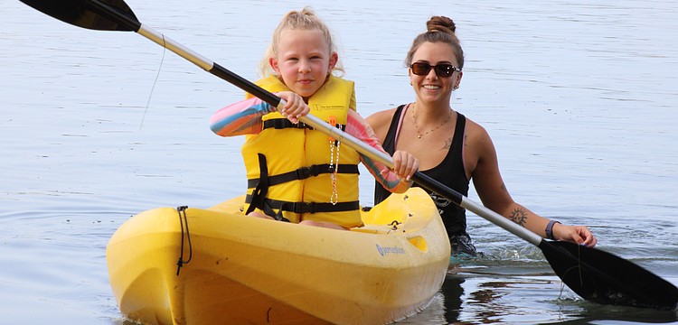 Poppy Otte paddles through the water while Mote Education Specialist Morgan Swartz helps.