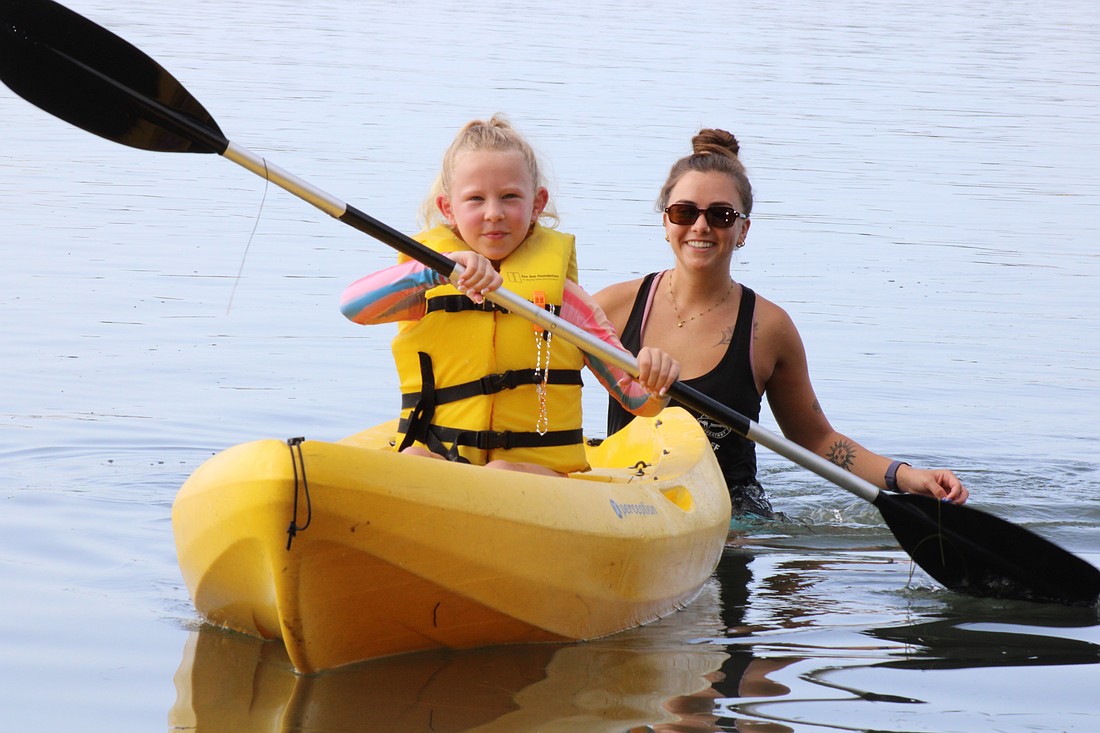 Poppy Otte paddling through the water while Mote Education Specialist Morgan Swartz helps.