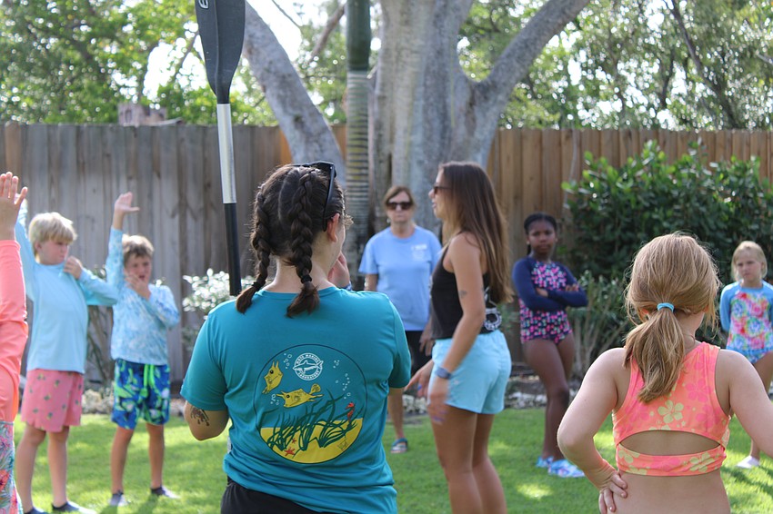 Camp counselors and educators Sophie Green and Morgan Swartz teach campers how safely and properly paddle on a kayak.