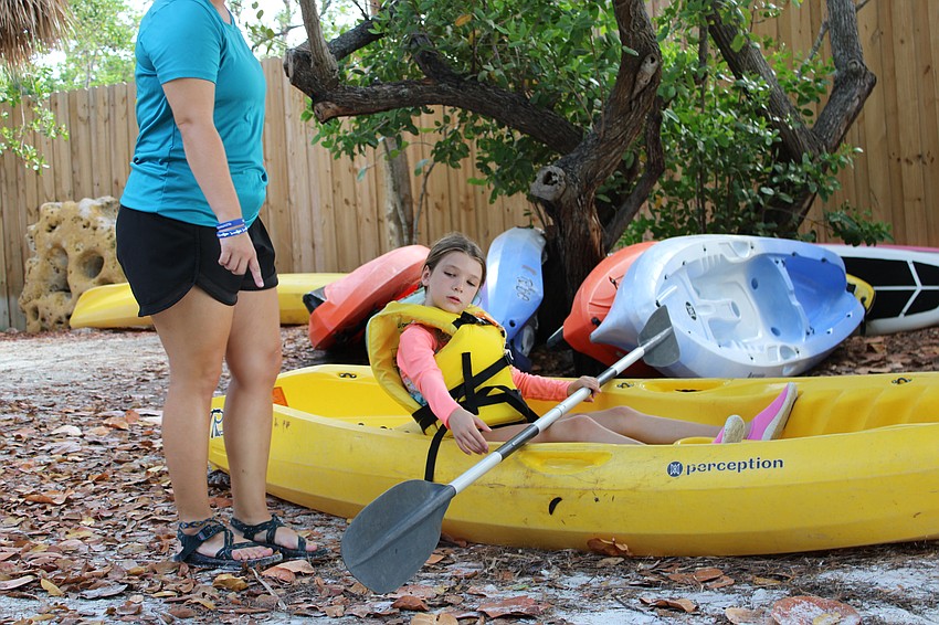 Camp counselor Sophie Greenwood reviews with camper Coco Olson the different ways of paddling in the water.