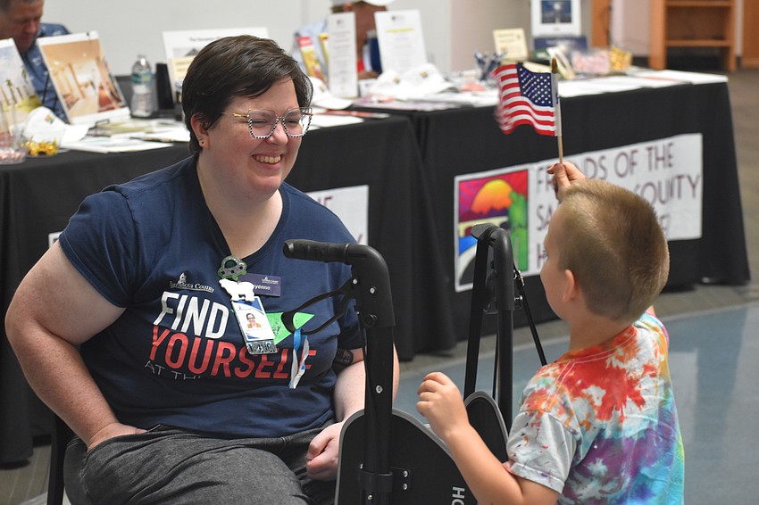 Alex Walker, 6, shows a flag to Sheyenne Scott, who is staffing the community art gallery.