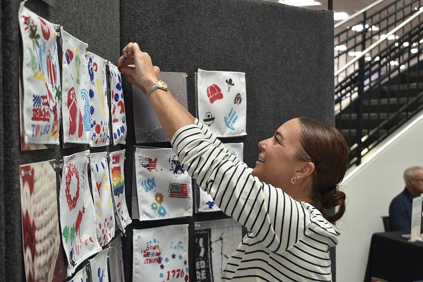 Courtney Robb hangs a painting in the community art project.