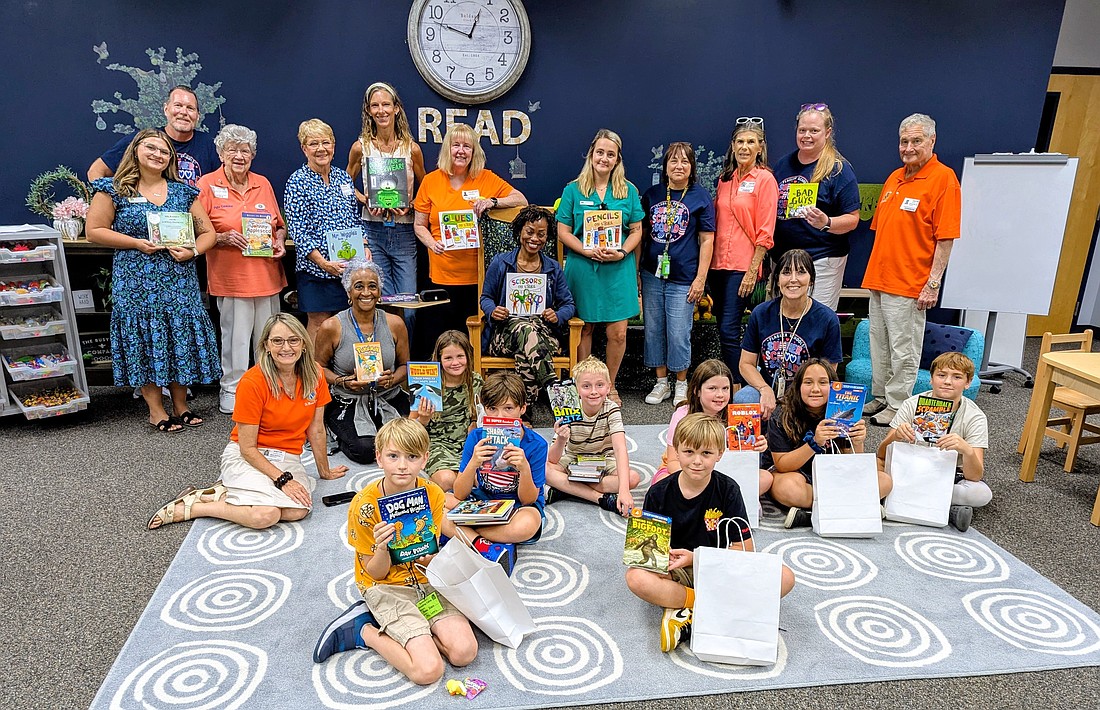 Summer Reading camp participants hold up their books along with Flagler Palm Coast Kiwanis Club members, teachers and volunteers at the club's annual "Library of My Own" book give-away. Photo by Brent Woronoff