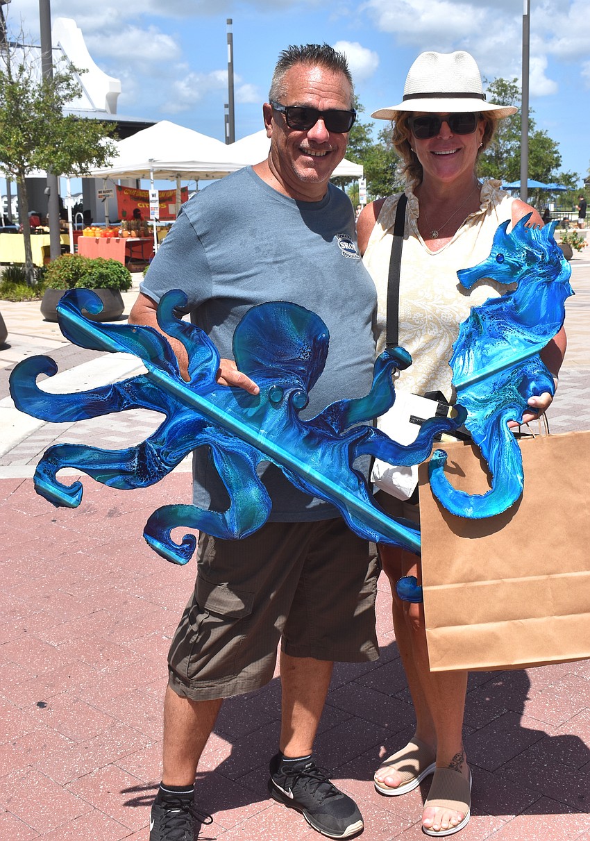 Palmer Ranch's Steve Mock and Marygrace Fot are excited to go home with octopus and seahorse art pieces from 10th Avenue West, made out of tin roofing.
