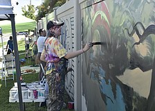 Ginger Kreithen works on "The Legacy," amid other artists at the wall.