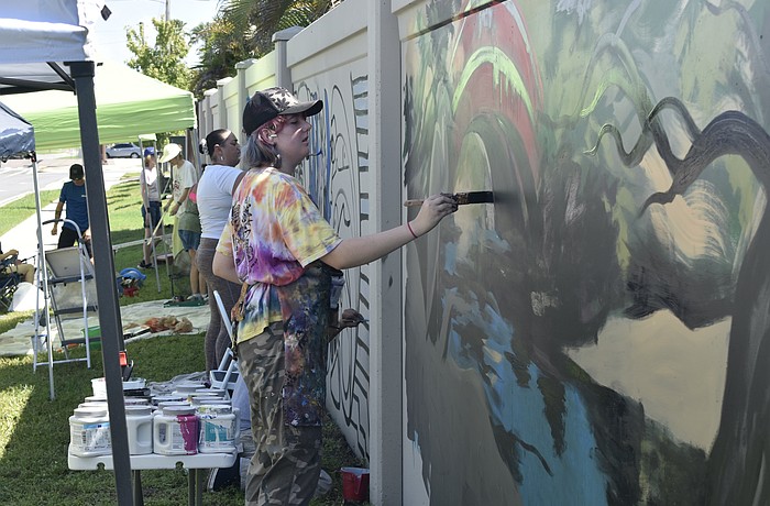 Ginger Kreithen works on "The Legacy," amid other artists at the wall.