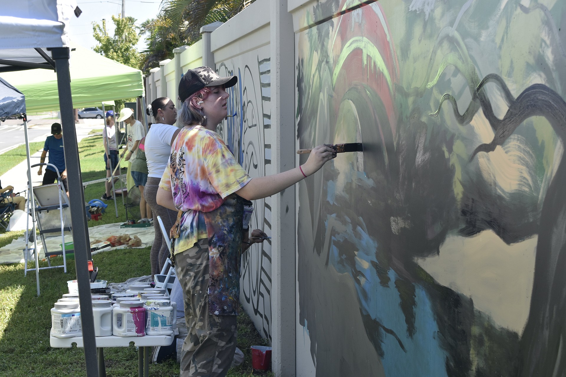 Ginger Kreithen works on "The Legacy," amid other artists at the wall.