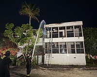 A firefighter sprays the roof of a Dock on the Bay condo building Wednesday morning, July 15.