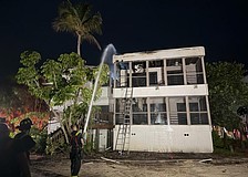 A firefighter sprays the roof of a Dock on the Bay condo building Wednesday morning, July 15.