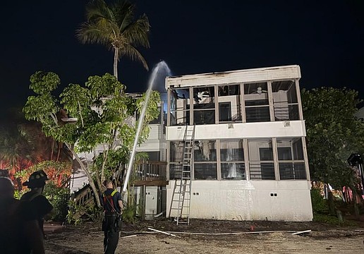 A firefighter sprays the roof of a Dock on the Bay condo building Wednesday morning, July 15.