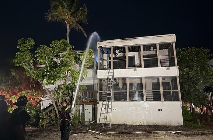 A firefighter sprays the roof of a Dock on the Bay condo building Wednesday morning, July 15.
