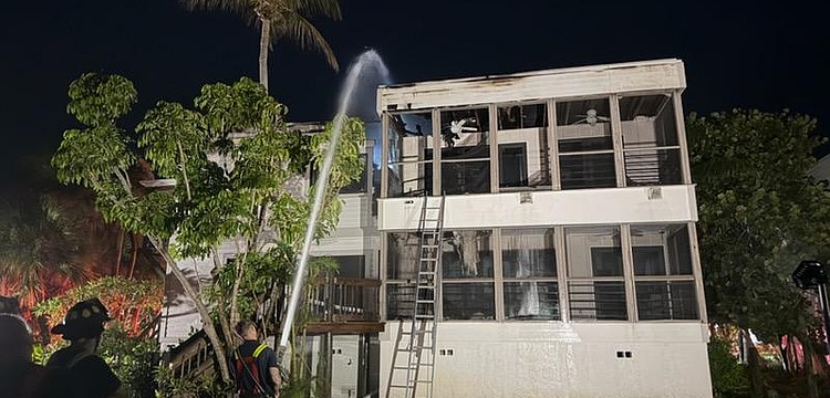 A firefighter sprays the roof of a Dock on the Bay condo building Wednesday morning, July 15.