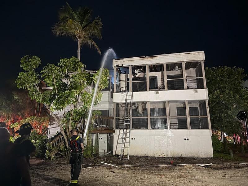 A firefighter sprays the roof of a Dock on the Bay condo building Wednesday morning, July 15.