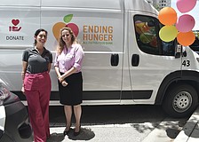 Amanda Eyer, internal communications and community relations director at Boar’s Head and Amber Lee, senior director of programs at All Faiths Food Bank, stand in front of one of the new vans.