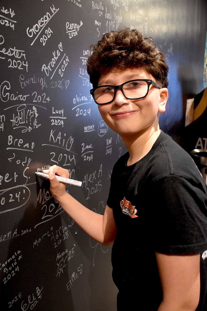 Lakewood Ranch's Mason Garcia, 12, is learning bass and signs his name to the wall of past students who have performed with School of Rock.