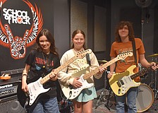Addison Gutowitz, 13, and Harriet Shore, 11, learn skills on electric guitar from 17-year-old Max Froemel in the guitar breakout session.