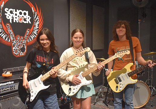 Addison Gutowitz, 13, and Harriet Shore, 11, learn skills on electric guitar from 17-year-old Max Froemel in the guitar breakout session.