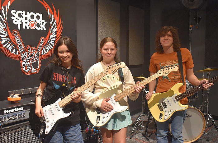 Addison Gutowitz, 13, and Harriet Shore, 11, learn skills on electric guitar from 17-year-old Max Froemel in the guitar breakout session.