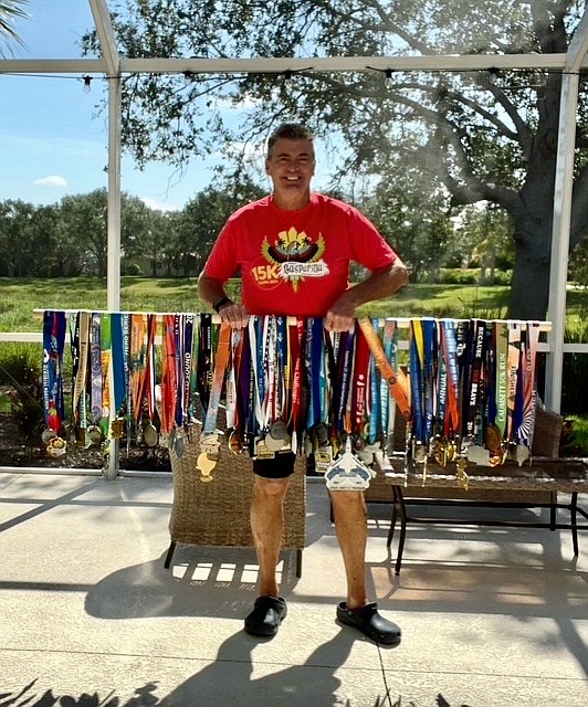Runner Vinny O'Shaughnessy stands with all the medals he gathered on his journey to finish a marathon in all 50 states.