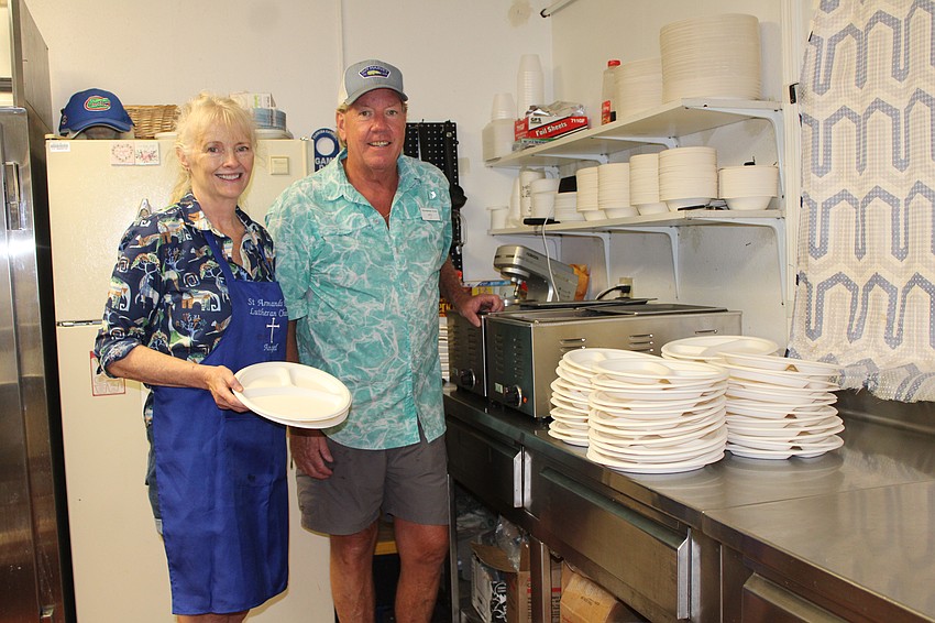 Karyn Smith helps deliver the St. Armands Key Lutheran Church-prepped food to Chef Pete Wallace at the Resurrection House, where he has a stack of plates waiting to be filled.
