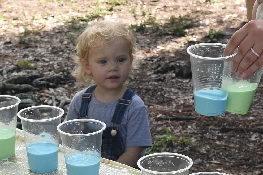 Farrah Lemay, 2, watches as her mother Rebekah Lemay picks up cups of liquid chalk.