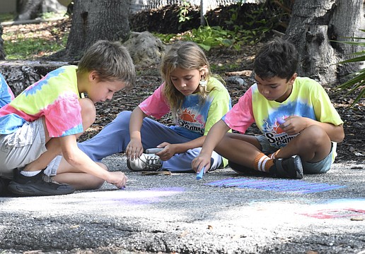Jared Thomas, 8; Penelope Brouillette, 7; and Sebastian Meehan, 8, chalk the trail together.