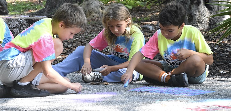 Jared Thomas, 8; Penelope Brouillette, 7; and Sebastian Meehan, 8, chalk the trail together.