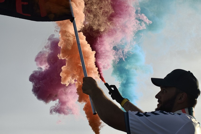 Nick Todisco waves a Sarasota Paradise flag as orange, pink and blue smoke fills the air. Before every home match, The Helm sets off smoke bombs coordinated with the team's colors.