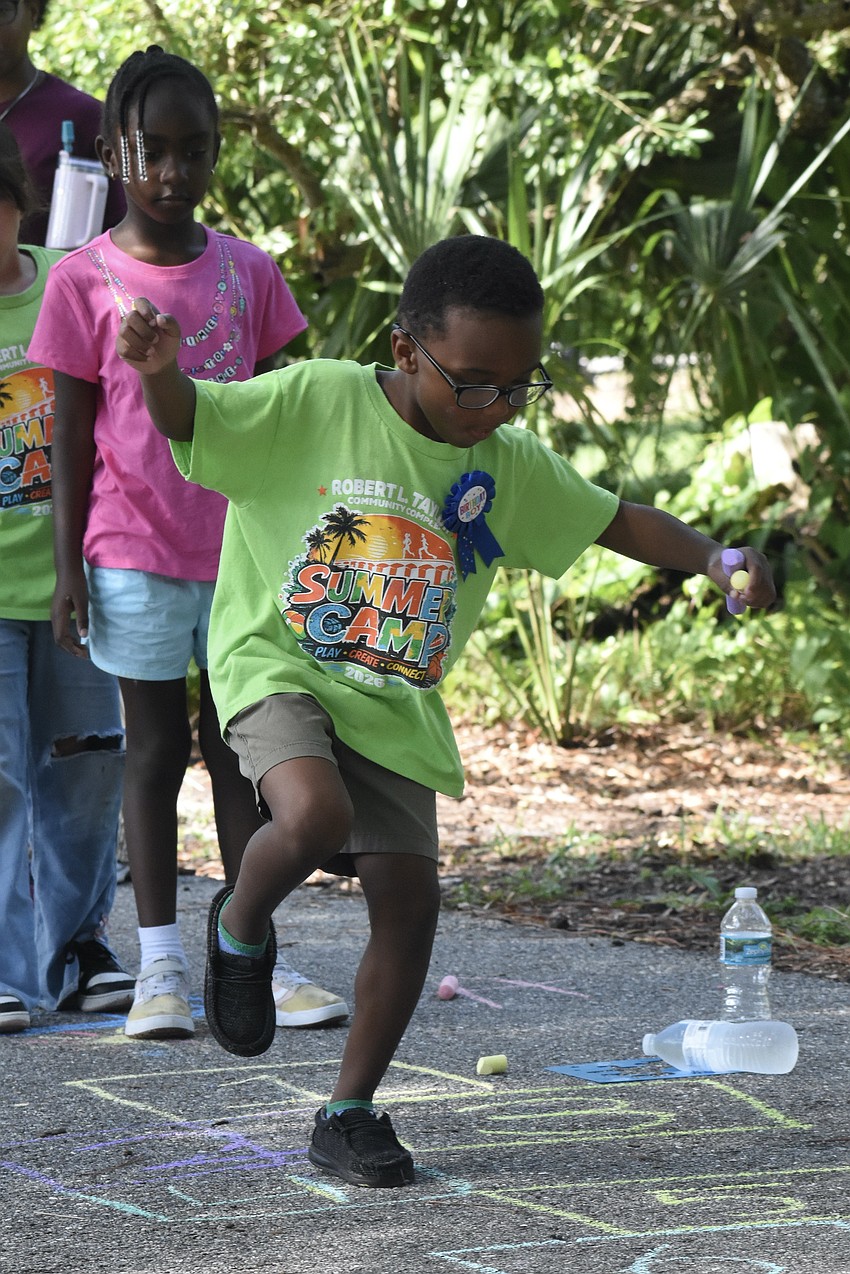 Beatrix Atkins, 6, and Jakhi Arthur, 6, join other campers in playing hopscotch.
