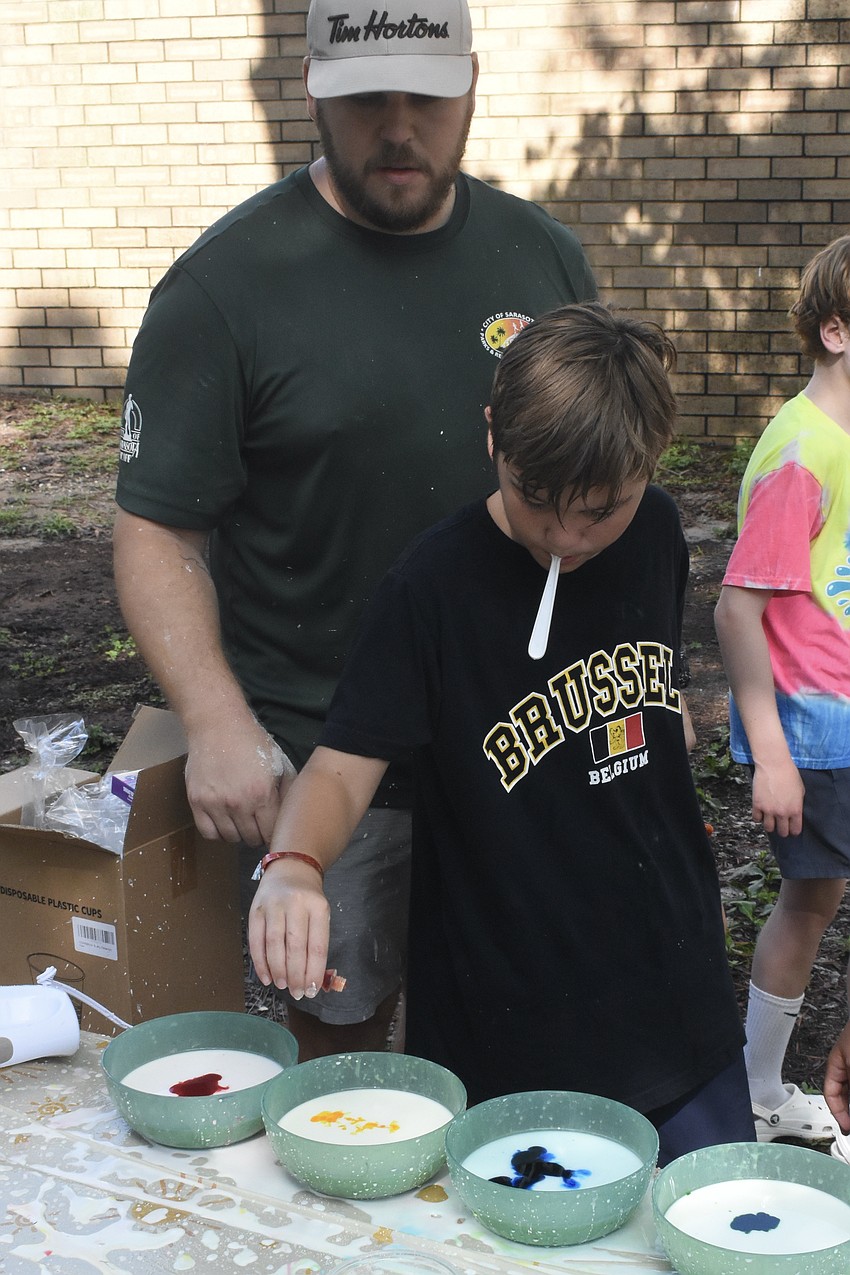 Kade Dean, 11, and Conner Bowers, recreation leader with Arlington Park and Aquatic Complex, mix up some liquid chalk.