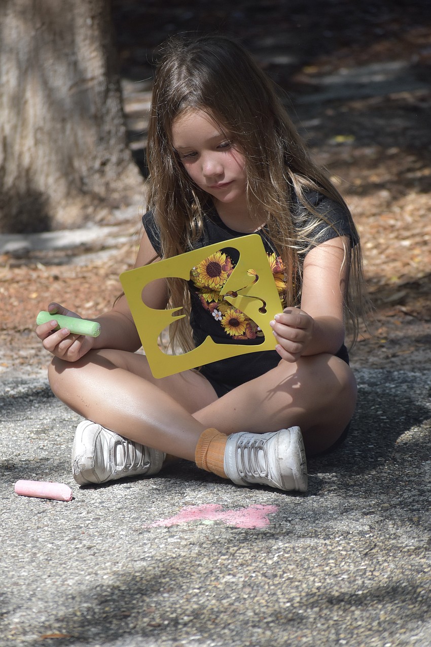 Ivy Beles, 6, looks over her stencil of a butterfly.