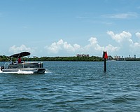 A pontoon boat passes a privately-installed navigation marker as it heads out to Sarasota Bay on July 22.