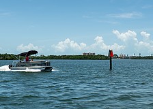 A pontoon boat passes a privately-installed navigation marker as it heads out to Sarasota Bay on July 22.