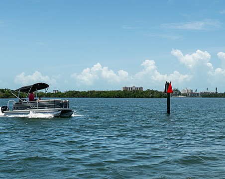 A pontoon boat passes a privately-installed navigation marker as it heads out to Sarasota Bay on July 22.