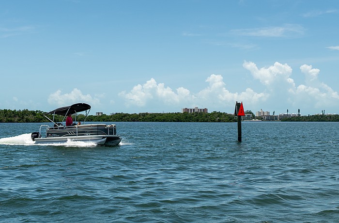 A pontoon boat passes a privately-installed navigation marker as it heads out to Sarasota Bay on July 22.