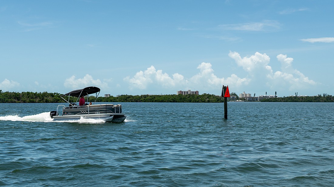 A pontoon boat passes a privately-installed navigation marker as it heads out to Sarasota Bay on July 22.