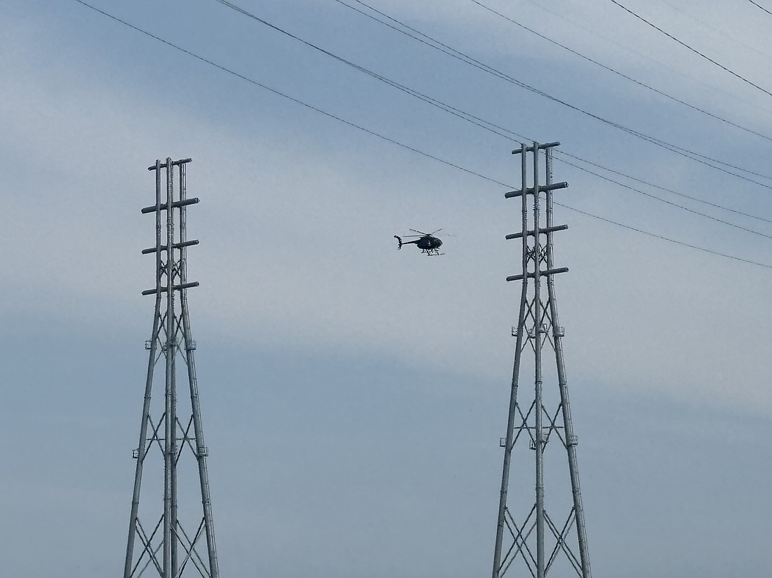 A helicopter performs initial inspection work on a new JEA tower on Blount Island.