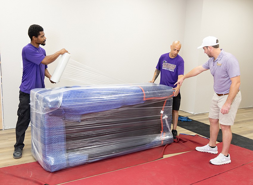 Angel Diaz, 31, (left) and Charles Valentin, 45, (middle) practice moving a couch inside the 2 College Brothers Moving and Storage warehouse with CEO Wade Swikle (right). Angel Diaz, 31, (left) and Charles Valentin, 45, (middle) practice moving a couch inside the 2 College Brothers Moving and Storage warehouse with CEO Wade Swikle (right).