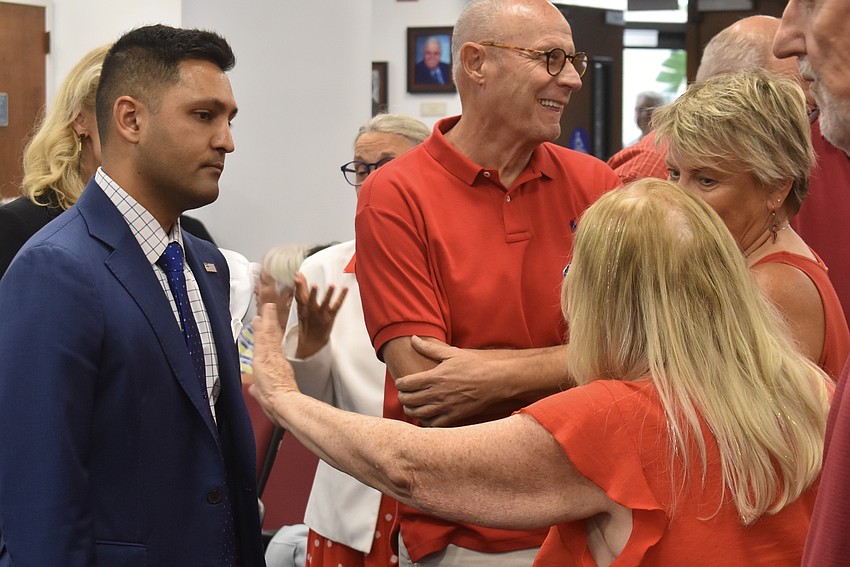 A group of red-shirted, Lakewood Ranch residents speak with Commission Chair Tal Siddique during a break in the meeting.