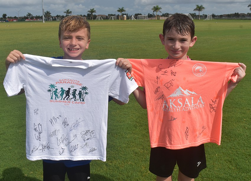 Lakewood Ranch 10-year-old Cooper Lux and Palmetto 8-year-old Eli Jacobs show off their shirts signed by Sarasota Paradise players.