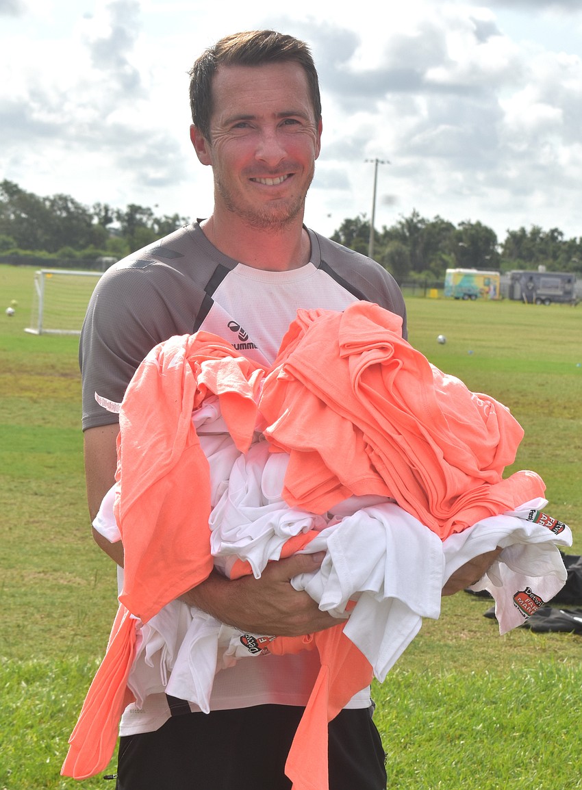 Junior Academy Director and Under 13 Head Coach Ross Hopkins gathers shirts for campers that will be signed by the Sarasota Paradise players.