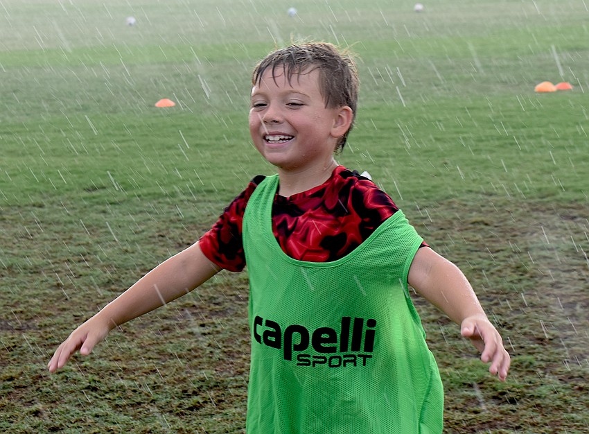 Lakewood Ranch 8-year-old Ryker Krawczyk says the rain felt nice enough to make him twirl and dance around during the soccer camp at Premier Sports Campus.