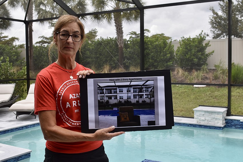 Esplanade at Azario resident Luzette Socash stands on her lanai, holding a rendering of what her backyard will look like if Pointe Grand Lorraine is built.