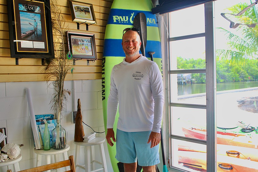 Shane Catts stands beside a collection of family pictures at the Happy Paddler Kayak Tours & Ecoventures store on Whitney Plaza. To his left is the canal, and to his right is a picture of him as a child visiting his grandparents' house, which is coincidentally right across the water. Shane Catts stands beside a collection of family pictures at the Happy Paddler Kayak Tours & Ecoventures store on Whitney Plaza. To his left is the canal, and to his right is a picture of him as a child visiting his grandparents' house, which is coincidentally right across the water.